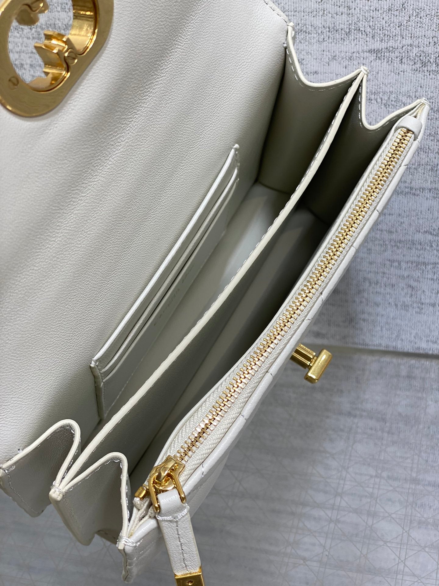 Dior handbag open interior view with white lining and gold zipper pull
