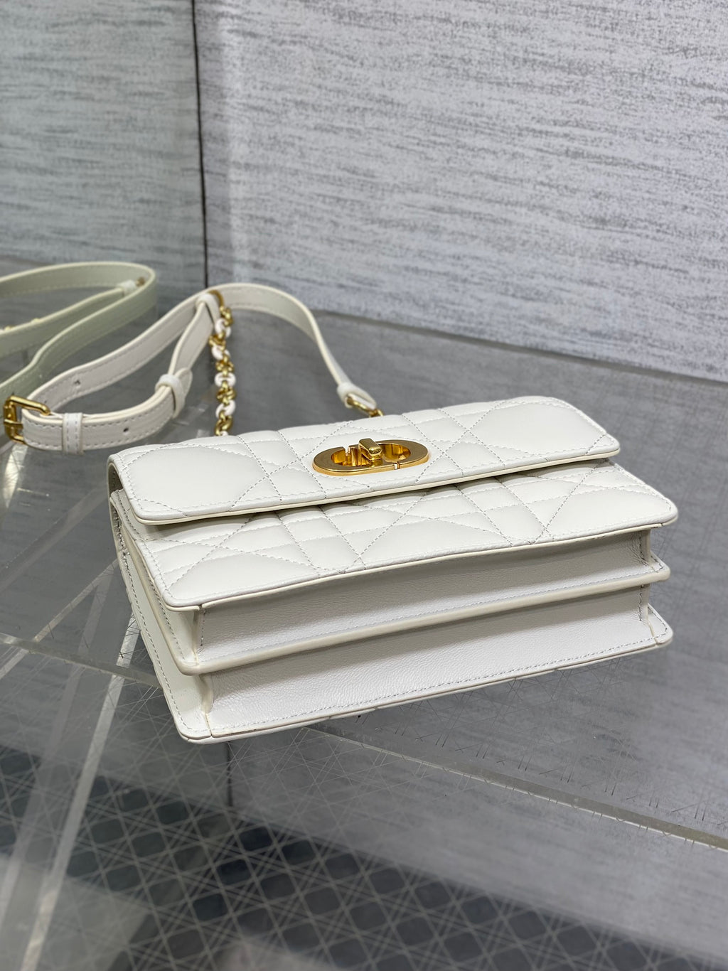 Dior handbag top view with white quilted leather and gold logo clasp