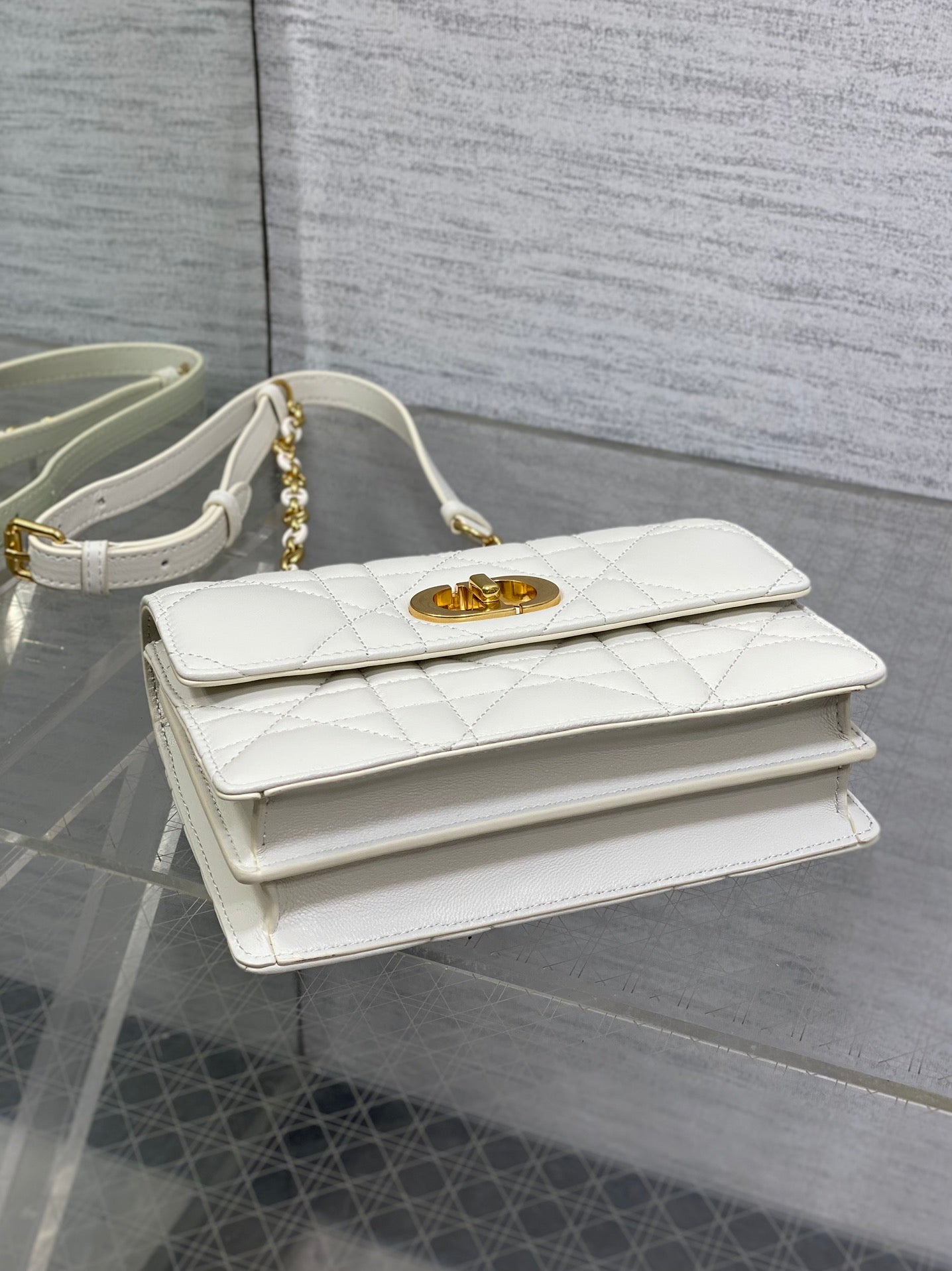 Dior handbag top view with white quilted leather and gold logo clasp