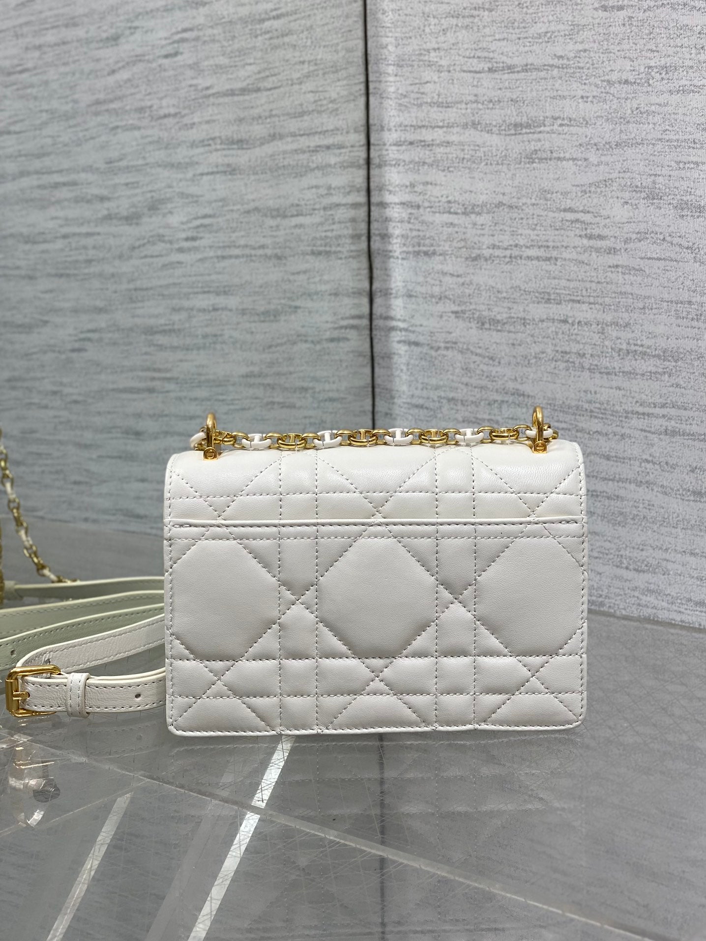 Dior handbag side view in white quilted leather with gold chain strap