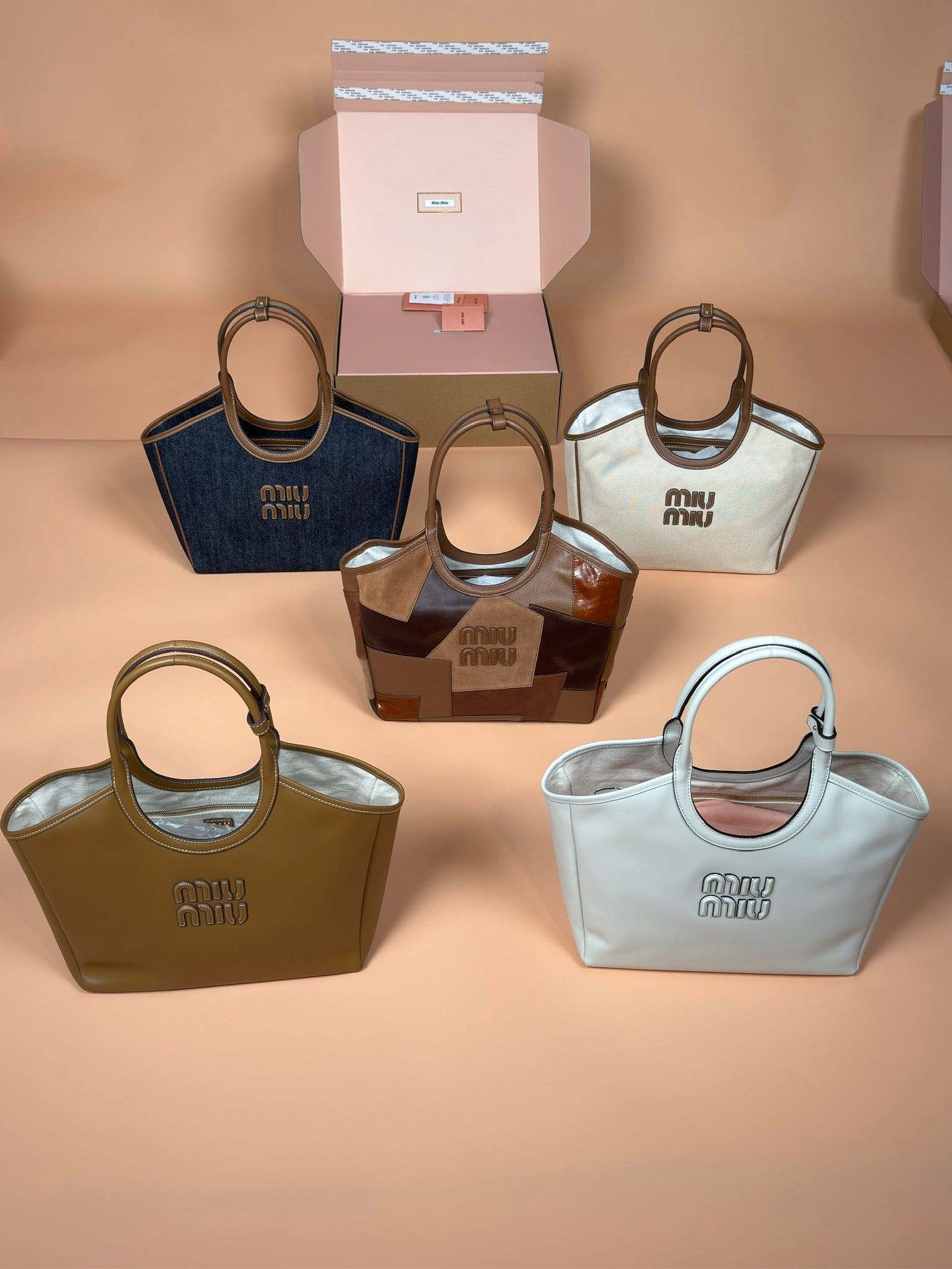 Assorted Miu Miu handbags, featuring navy, tan, olive, and light blue top handles