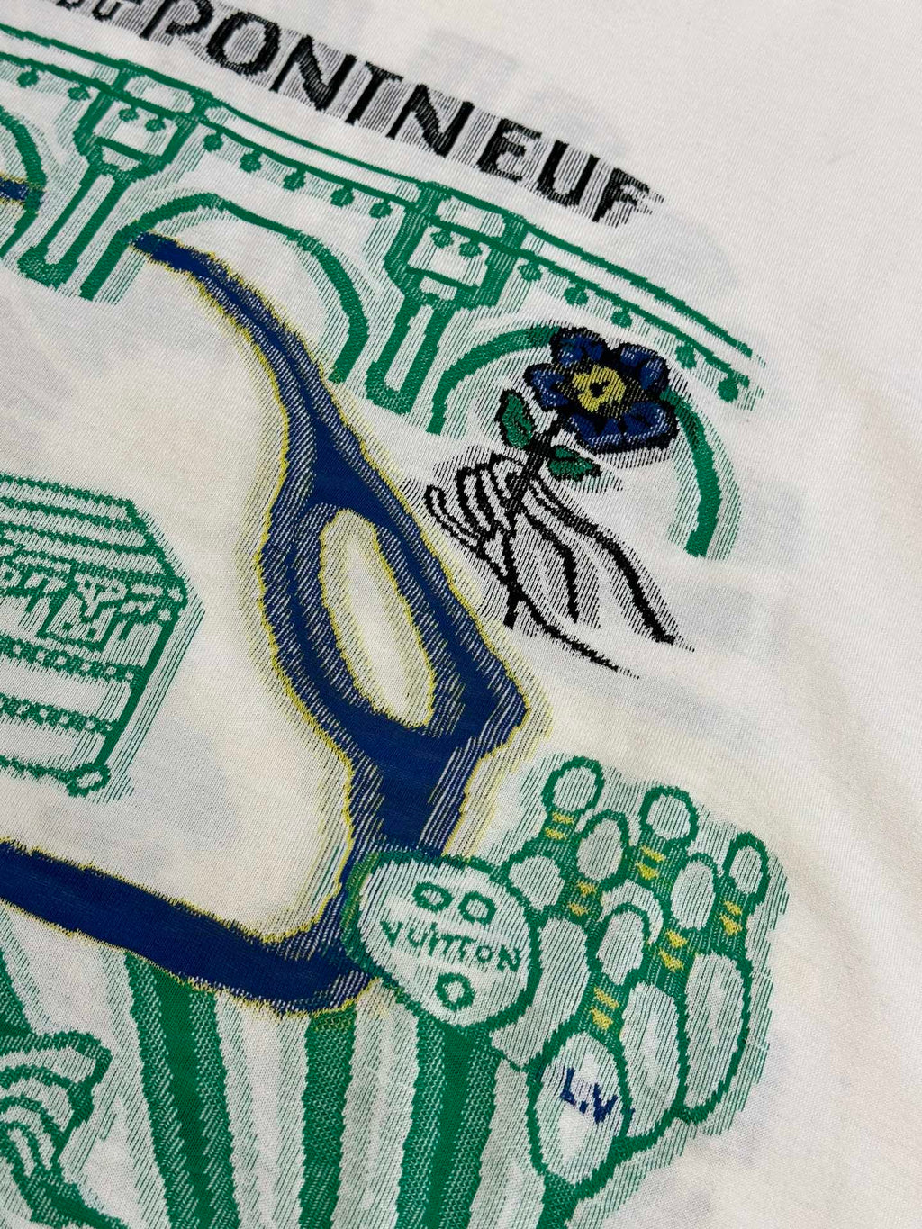 White T-shirt fabric with green and blue illustrated design near the chest