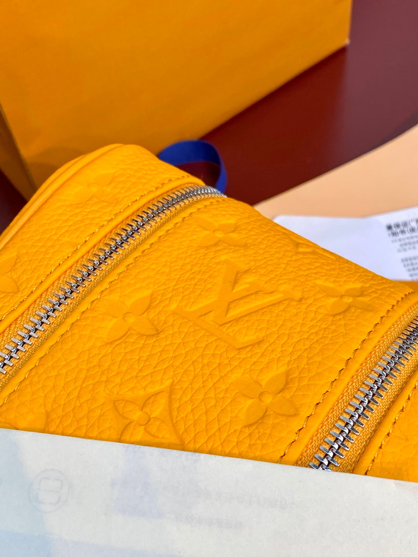Yellow Louis Vuitton pouch bag close-up with monogram embossing and shiny zipper teeth.