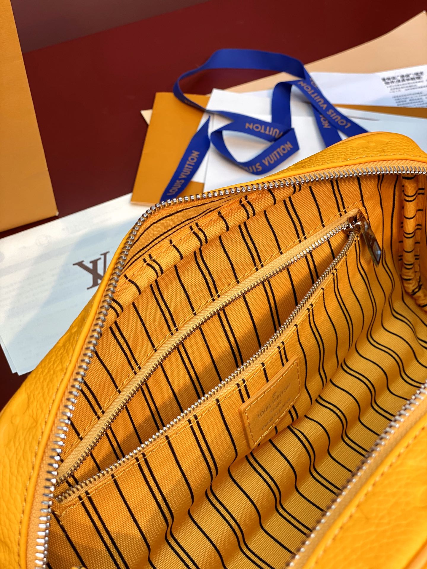 Yellow Louis Vuitton pouch bag interior with monogram lining and zipper edge.