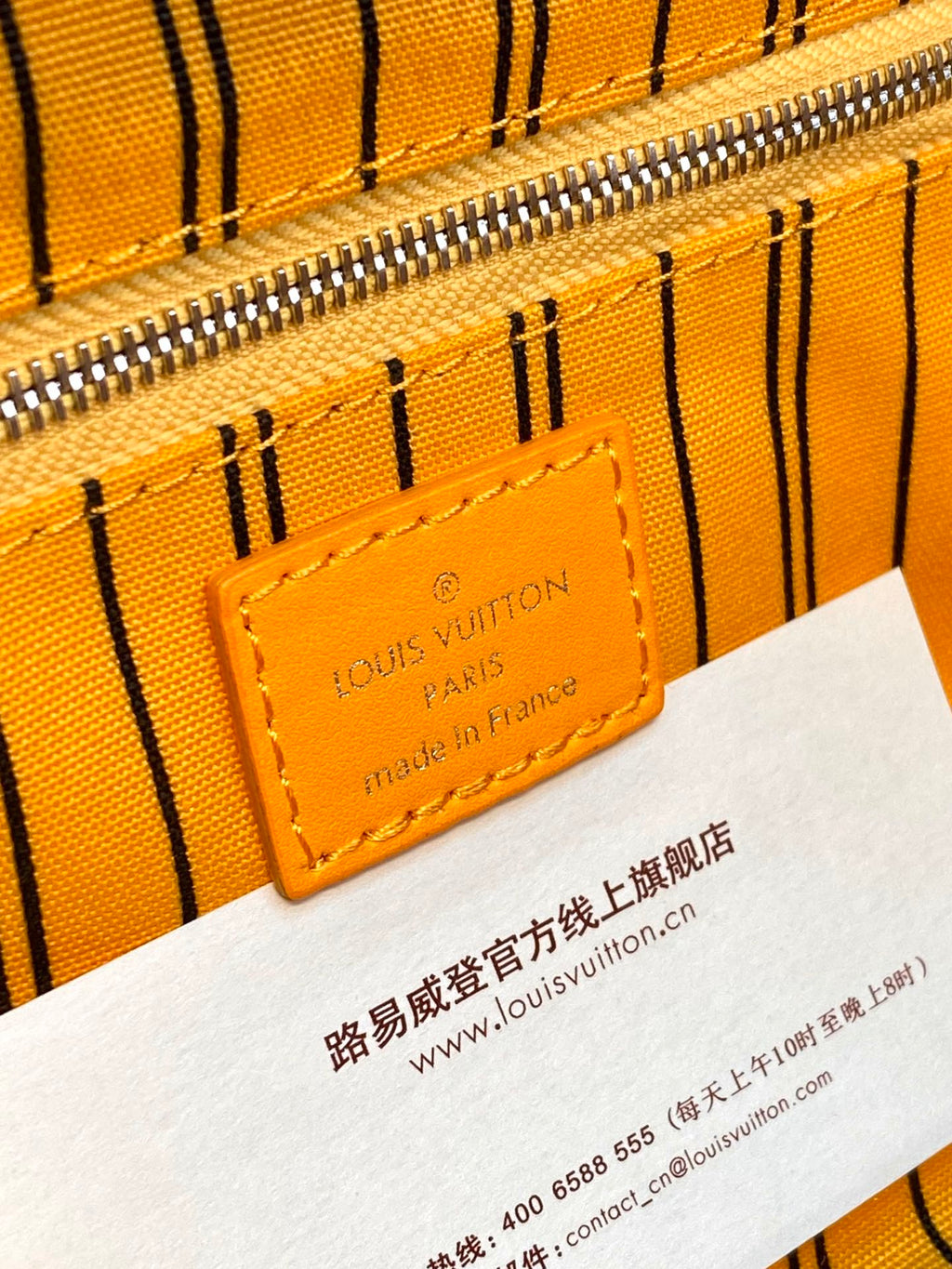 Louis Vuitton logo label on yellow monogram pouch bag with visible zipper track.