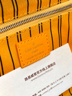 Louis Vuitton logo label on yellow monogram pouch bag with visible zipper track.