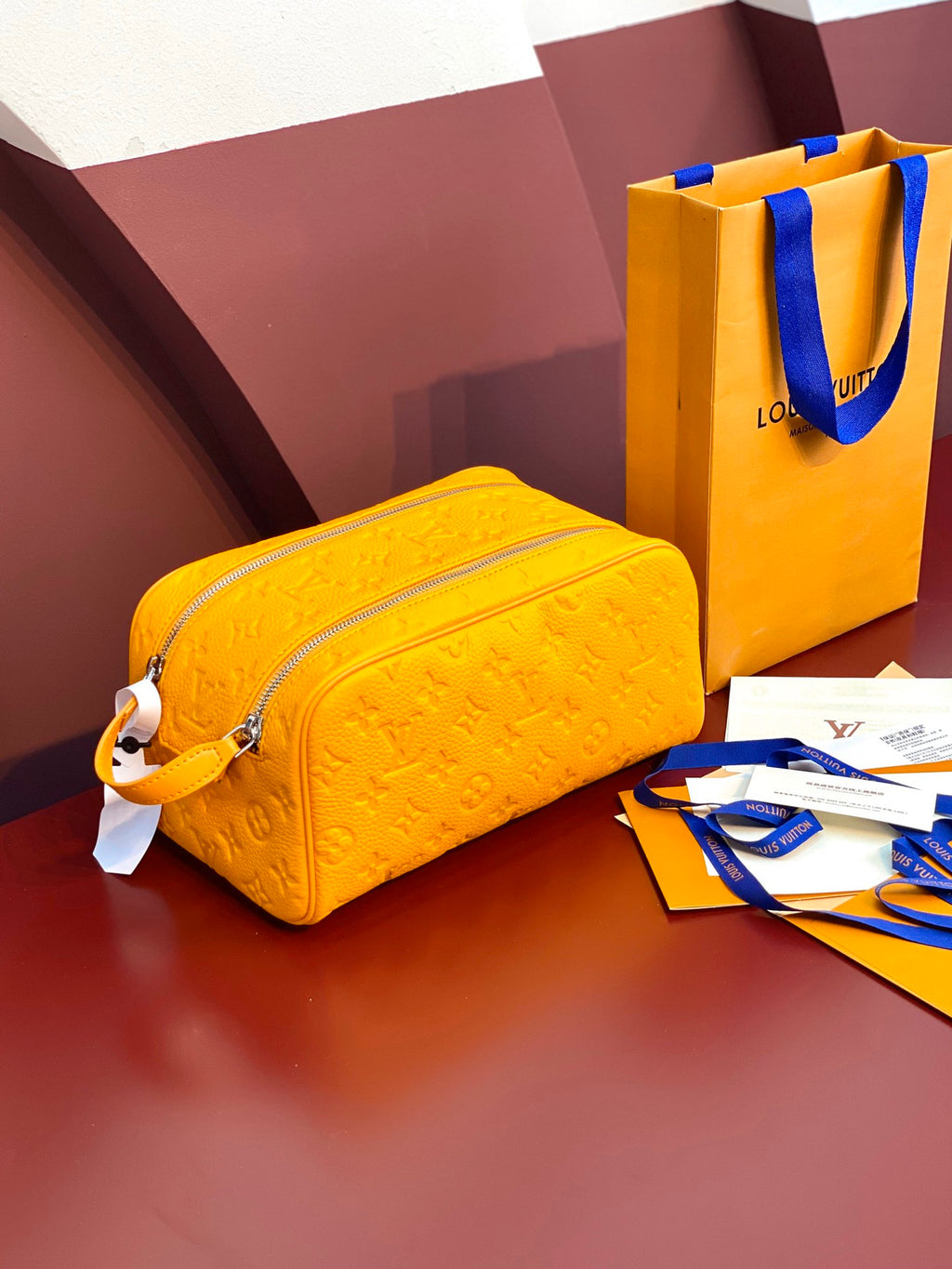 Yellow Louis Vuitton pouch bag with embossed monogram texture and zip closure.