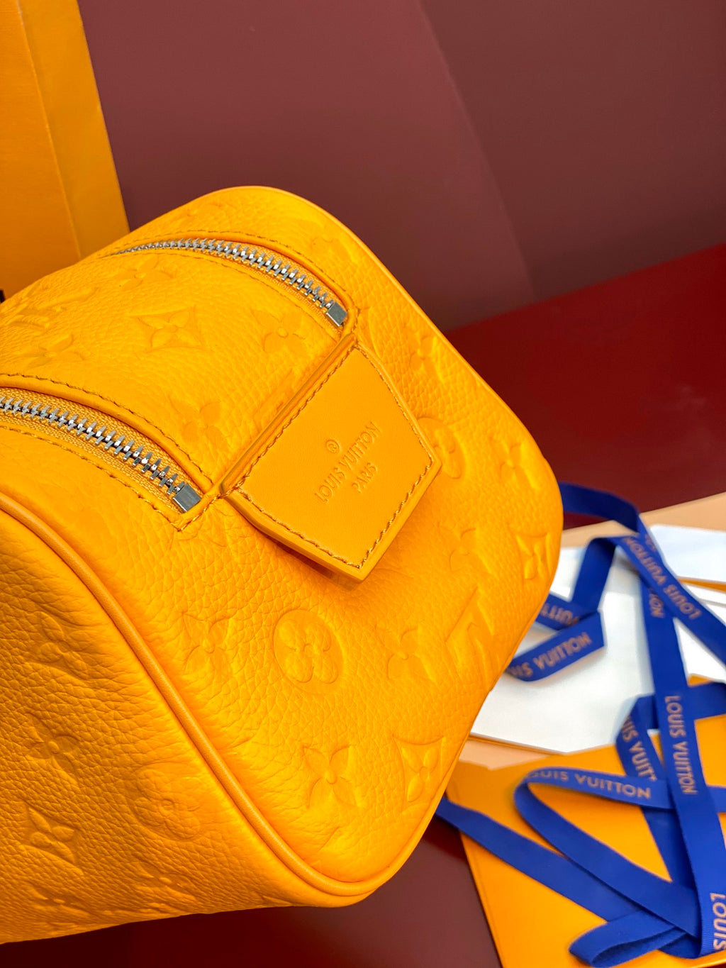Yellow Louis Vuitton pouch bag side view with embossed monogram and leather strap tab.