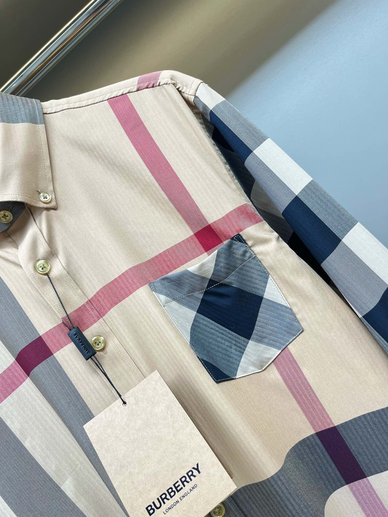 Burberry plaid shirt fabric close-up with pink and blue stripes, button placket