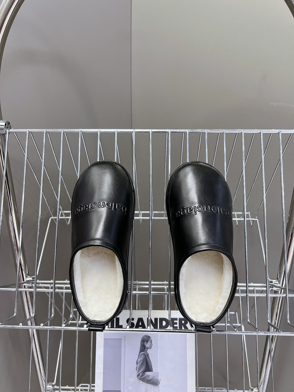 Black leather slide sandals with plush white interior lining
