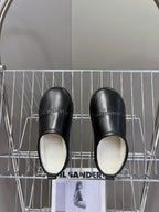 Black leather slide sandals with plush white interior lining