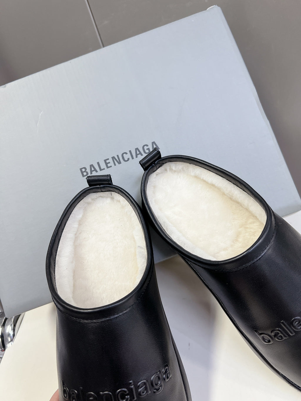 Black leather slide sandals showing plush white inner footbeds