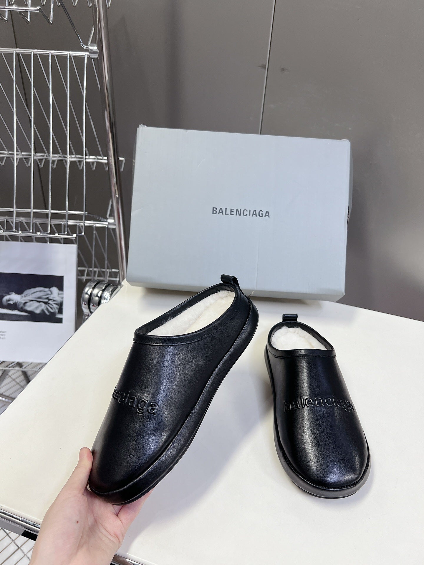 Black leather slide sandals, one hand-held with matching pair