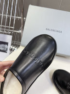 Black leather slide sandals with embossed logo text on upper