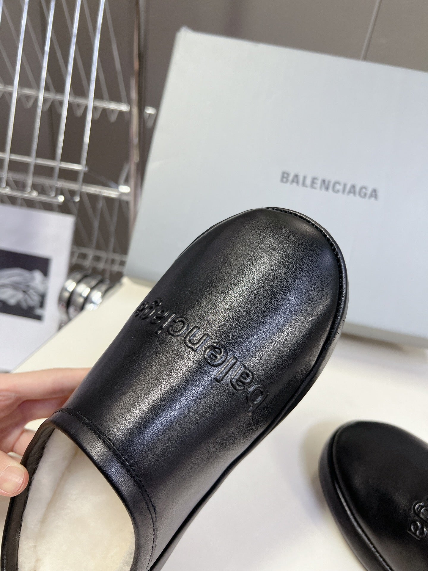 Black leather slide sandals with embossed logo text on upper