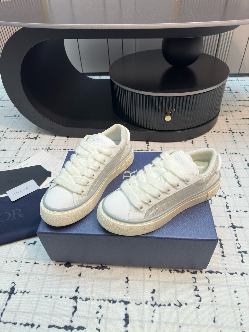 Dior unisex lace-up sneakers, white leather, profile view on display box