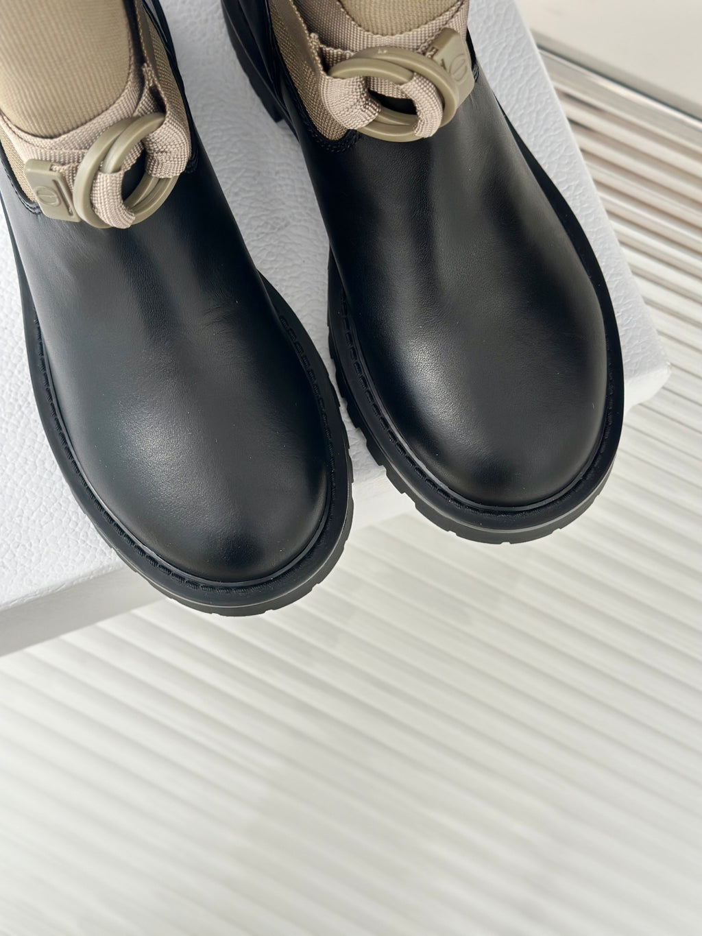Women’s Dior ankle boots close-up, black leather uppers with beige top cuff and buckle