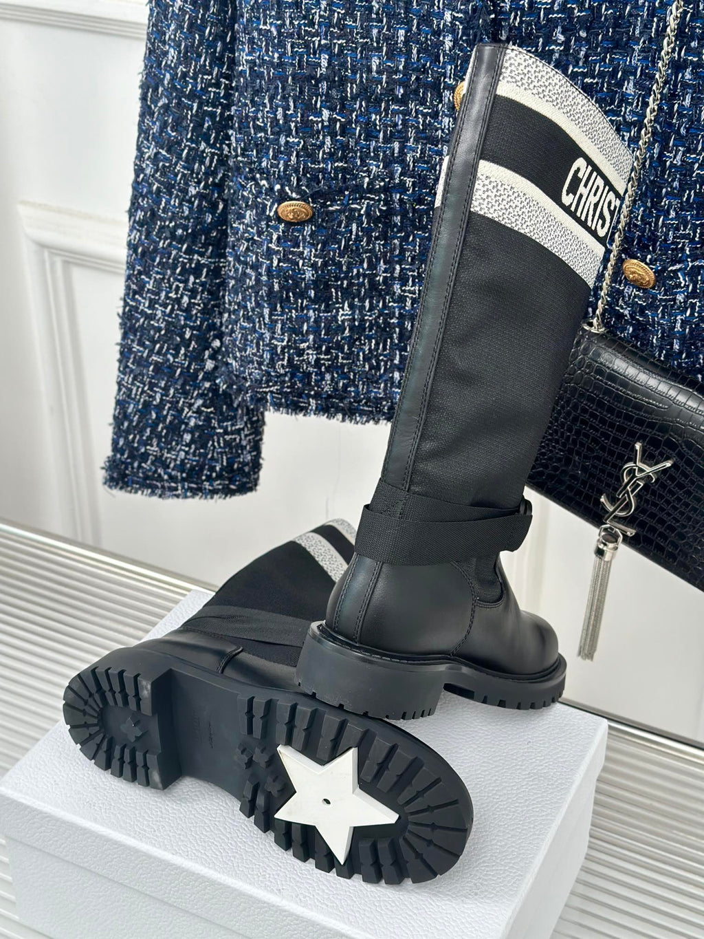 Black knee-high boots with thick tread sole and logo cuff