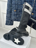 Black knee-high boots with thick tread sole and logo cuff