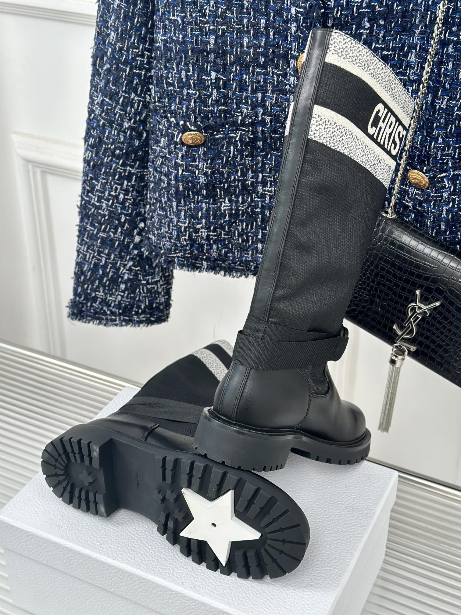 Black knee-high boots with thick tread sole and logo cuff