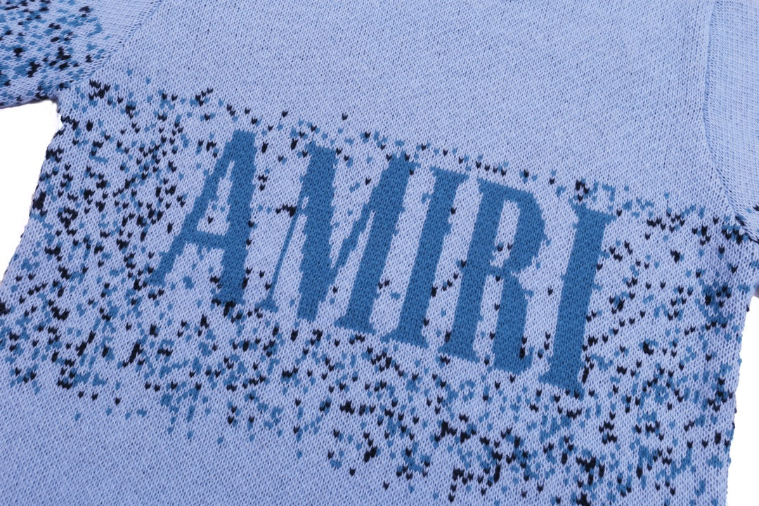 Light blue knit sweater front with large speckled AMIRI lettering