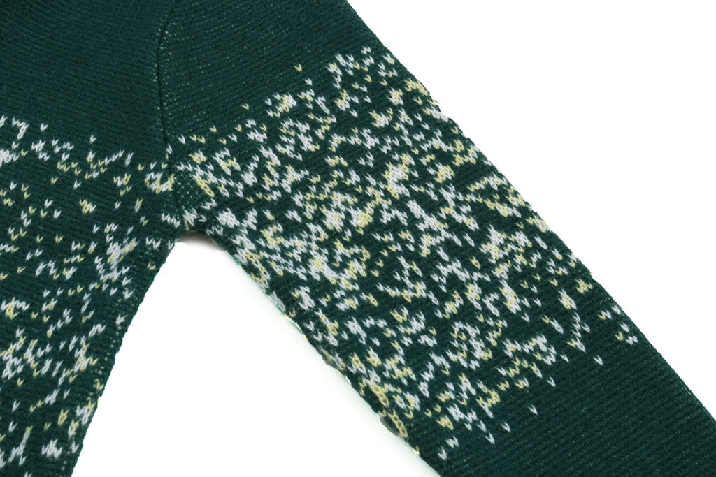 Green knit sweater sleeve with speckled pattern and ribbed cuff