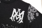 Black knit sweater front with white crest logo and small jacquard motifs