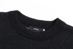 Black knit sweater neckline with ribbed collar and small AMIRI label