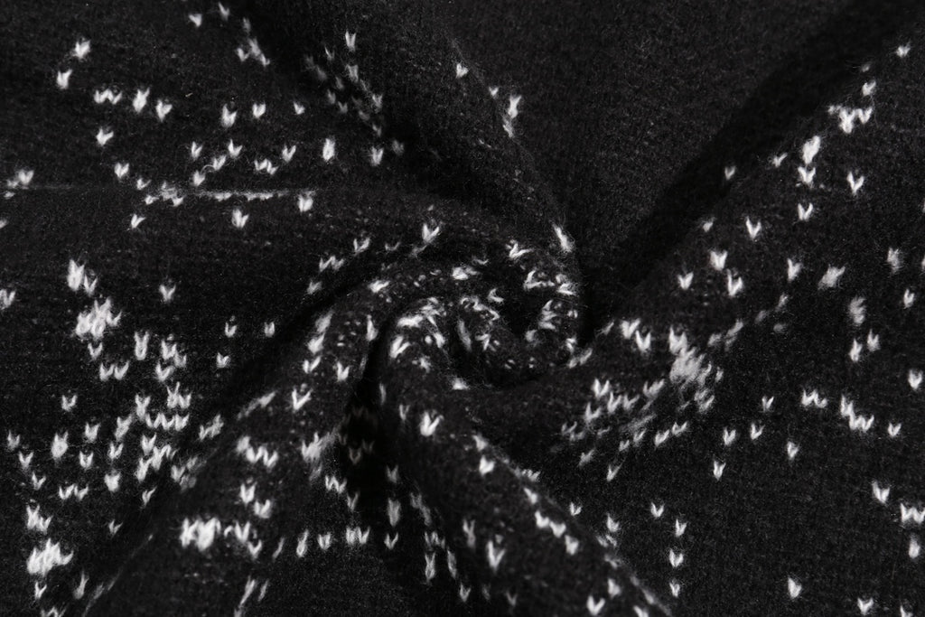 Black knit fabric with white jacquard pattern detail across the sweater