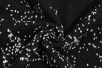 Black knit fabric with white jacquard pattern detail across the sweater