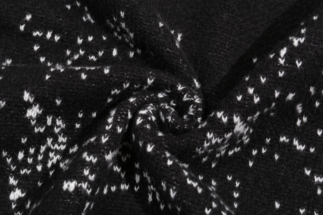 Black knit fabric with white jacquard pattern detail across the sweater