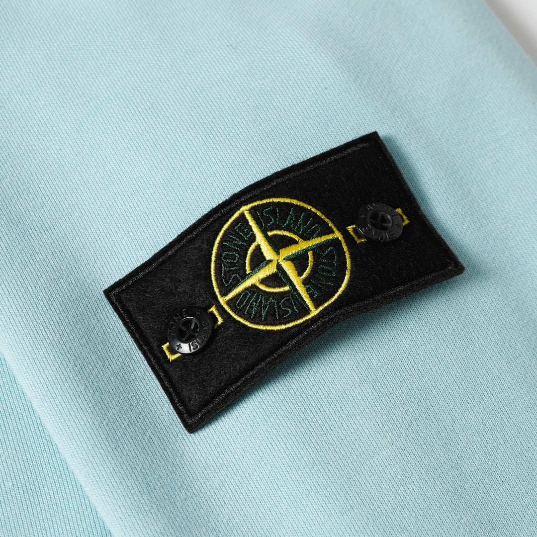 Light blue sweatshirt with embroidered yellow circular logo on a black patch