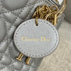 Dior charm on quilted handbag lining, featuring "Christian Dior" text in gold on gray