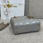 Dior quilted handbag with top handle and gold studs in light gray, back view