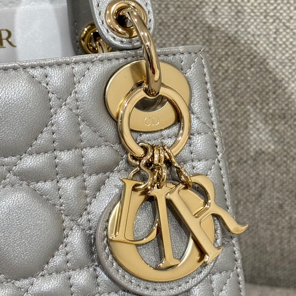 Gold "CD" charm and chain detail on light gray quilted Dior handbag