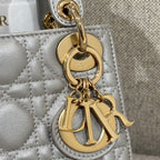 Gold "CD" charm and chain detail on light gray quilted Dior handbag