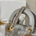Dior quilted mini handbag showing front handle rings and gold chain strap in light gray