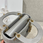 Dior quilted handbag with open top, gold rings, and chain strap in light gray