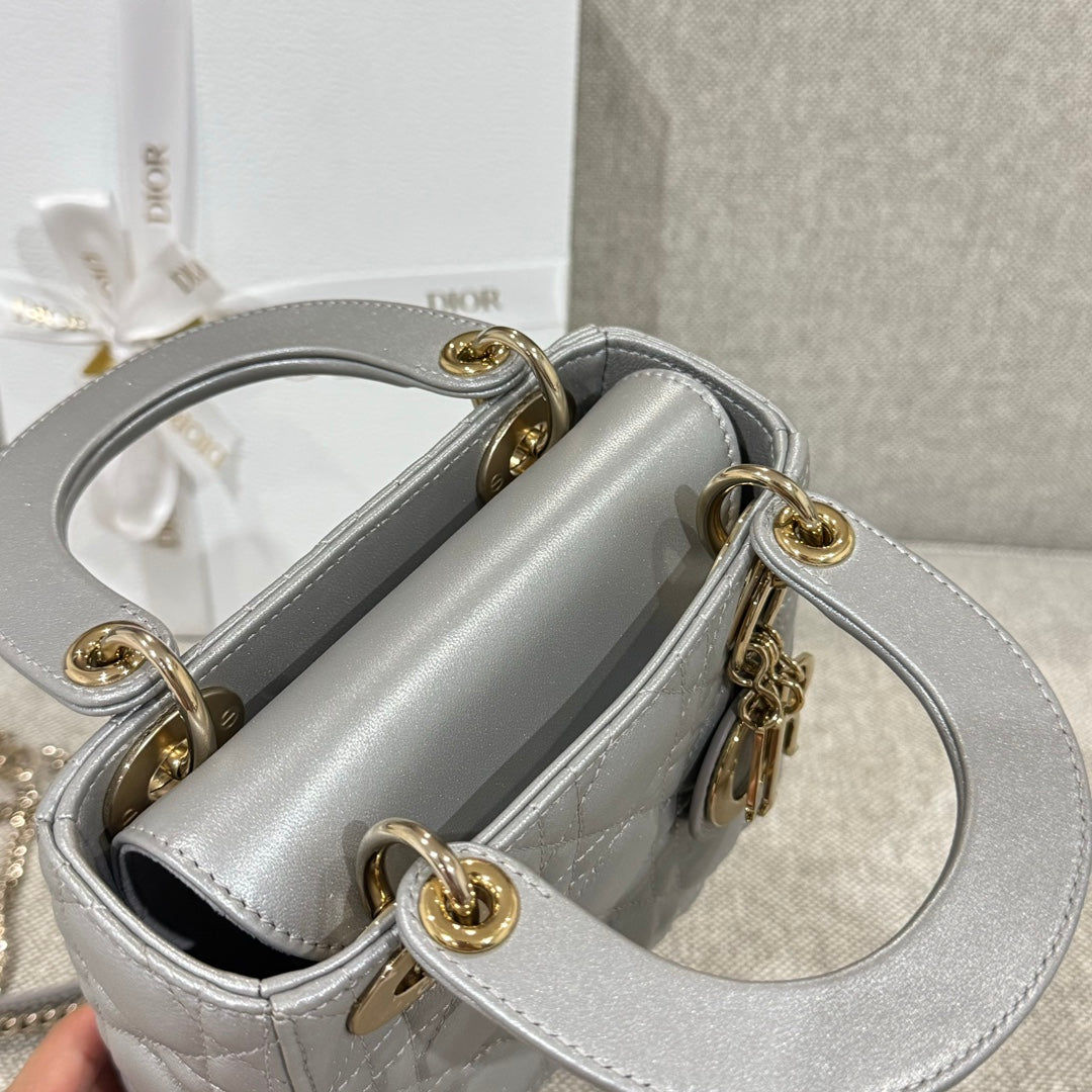 Dior quilted handbag with open top, gold rings, and chain strap in light gray