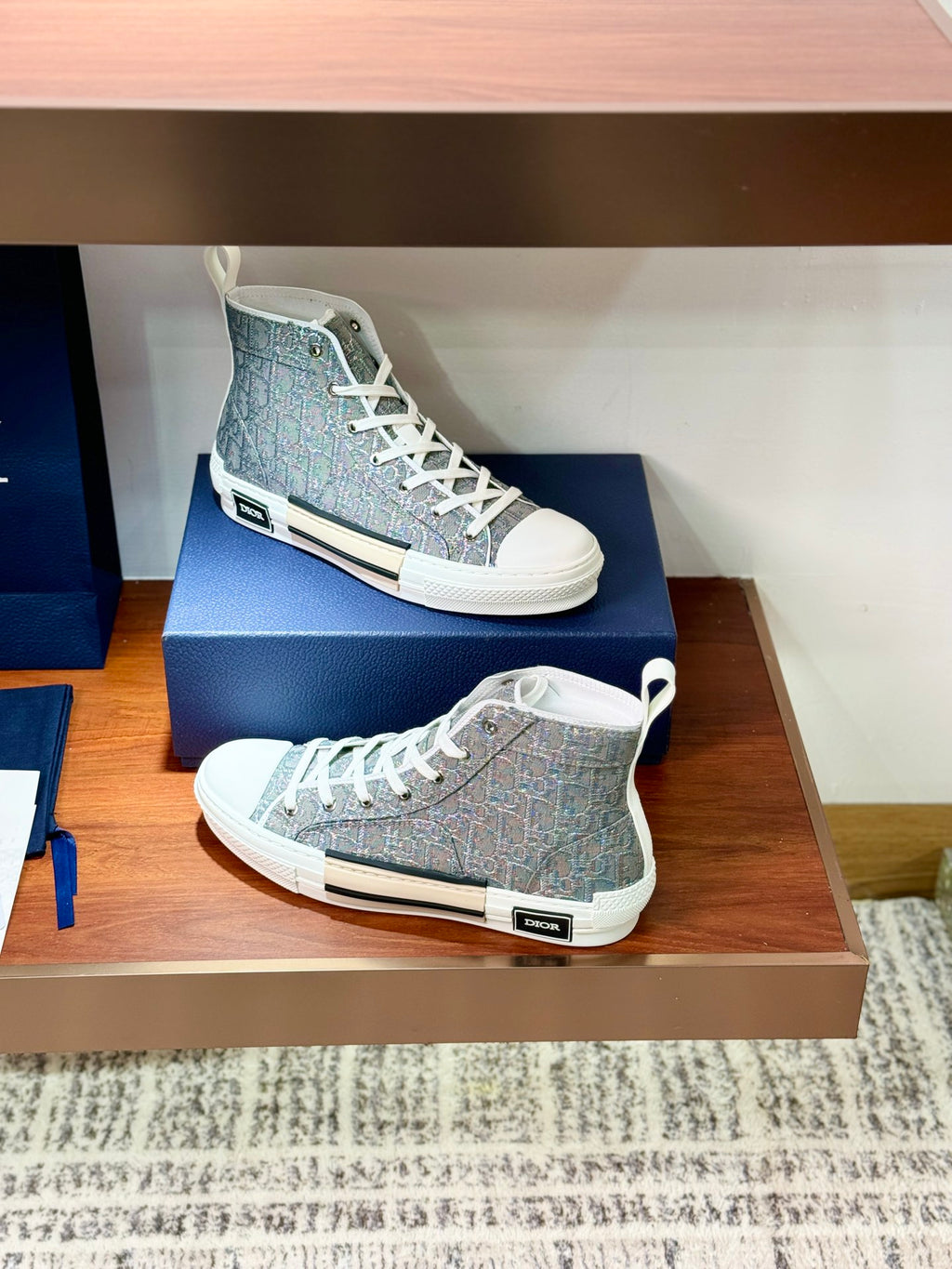 Women's gray-blue patterned high-top sneakers with white laces on display shelf