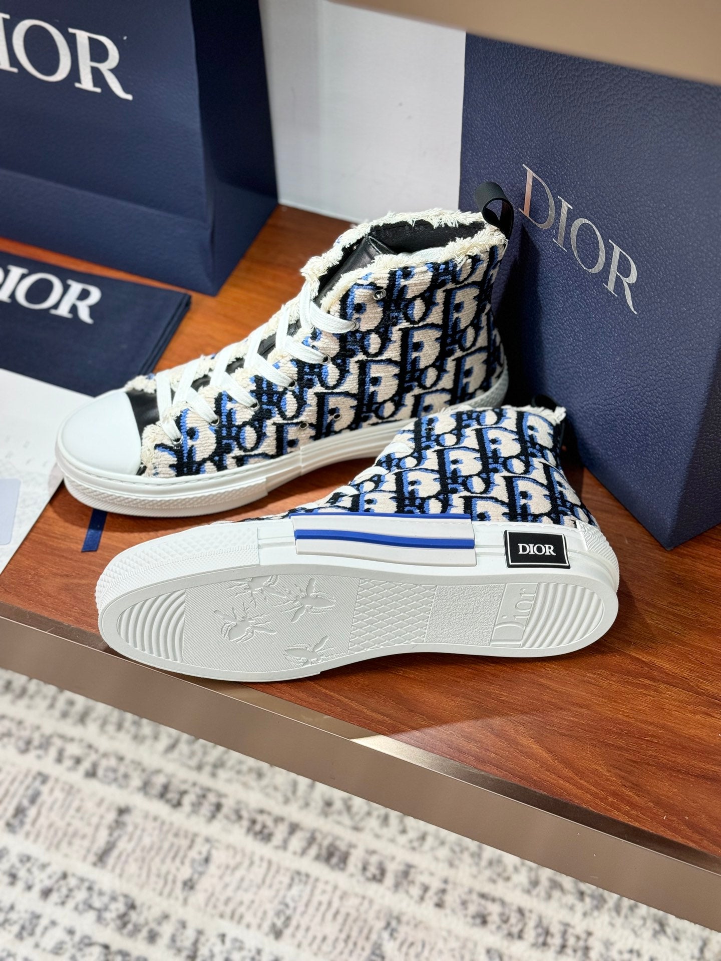 Dior high-top sneakers with blue monogram print, soles facing camera