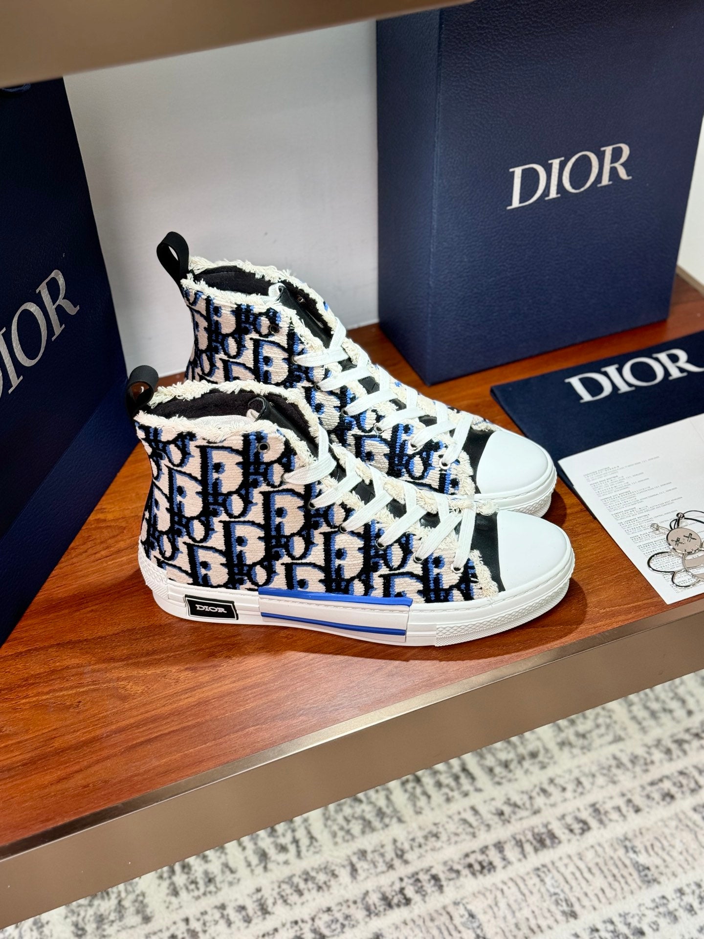 Dior high-top sneakers, angled front view, blue monogram print and white lace-up