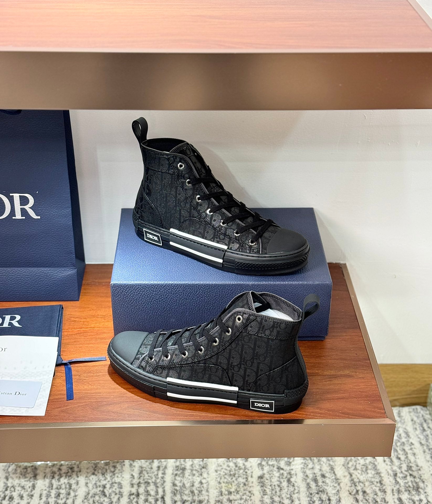 Ladies dark lace-up high-top sneakers, one upright and one angled on display
