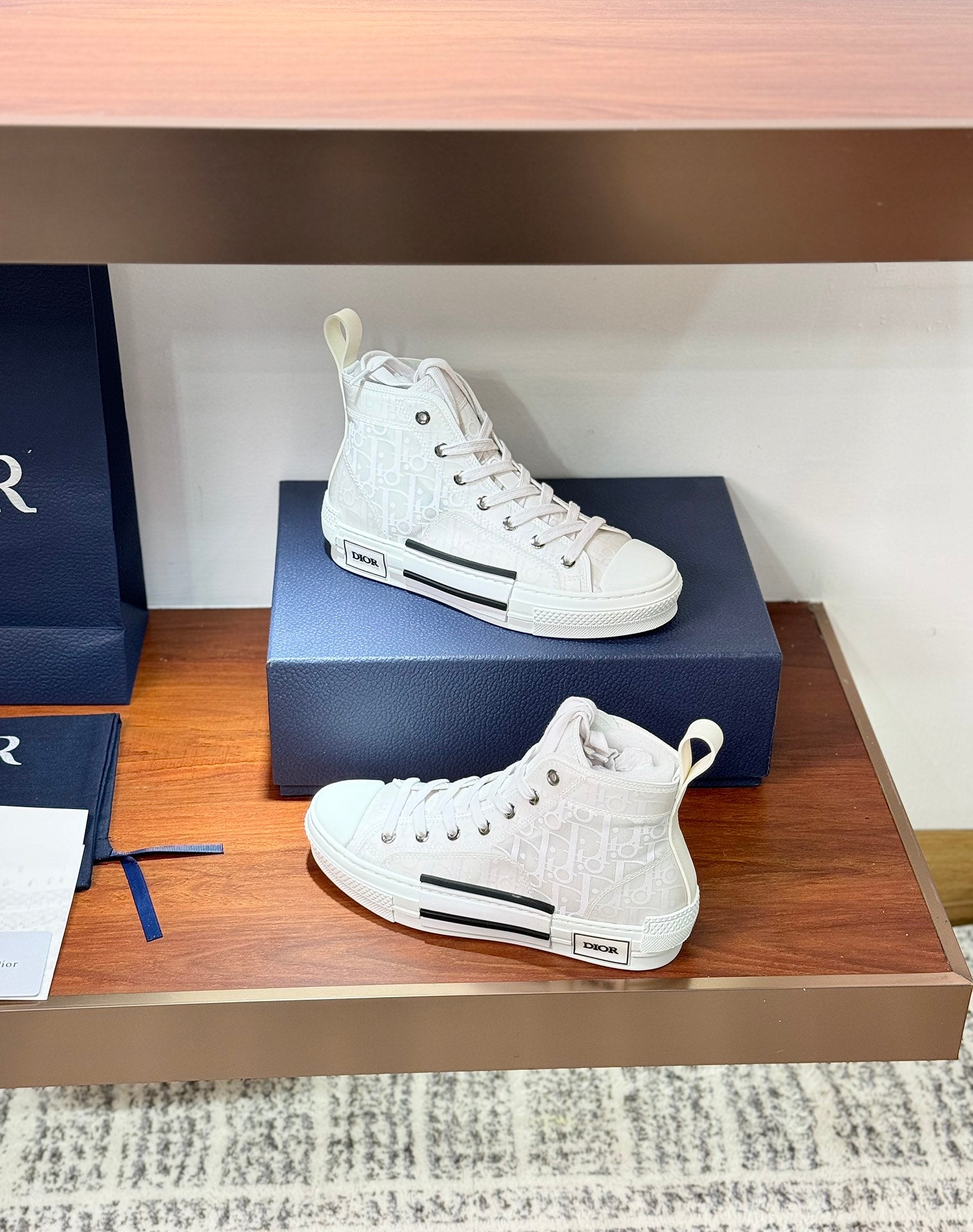 Dior white high-top lace-up sneakers on display, heel and side logo patch visible