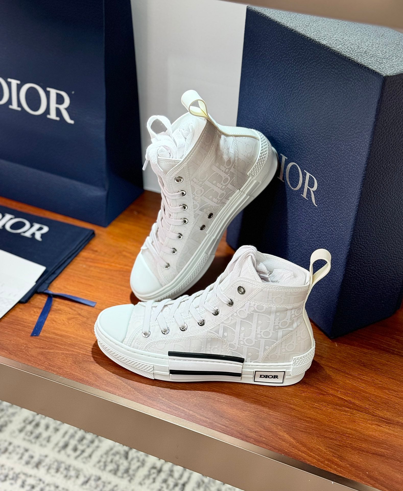 Dior white high-top lace-up sneakers pair with textured upper and black stripe