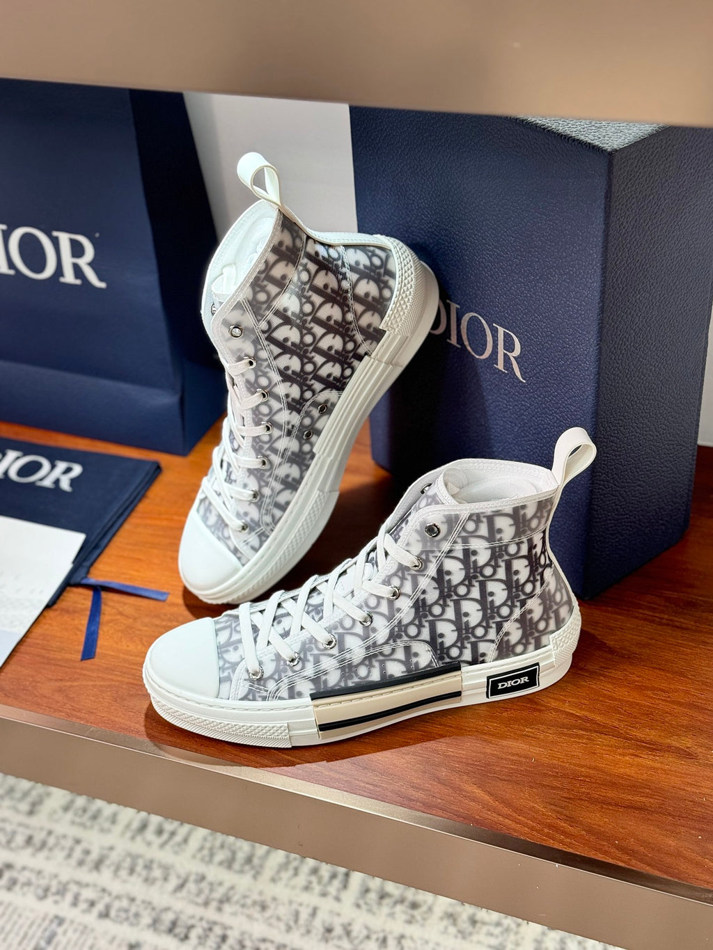 Two white Dior monogram high-top sneakers, front sides facing camera