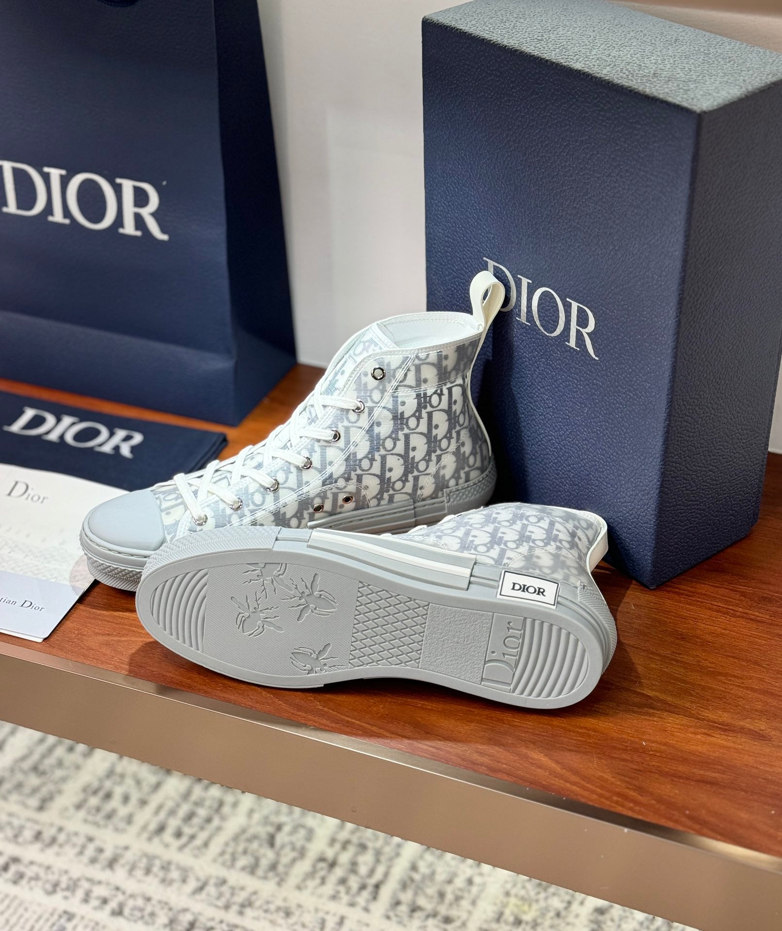 White Dior monogram sneakers with patterned outsole and embossed logo detail.