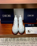 Pair of white high-top sneakers with Dior monogram print and lace-up design.
