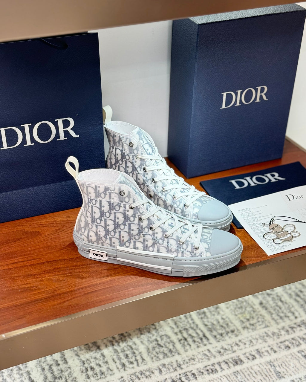 White high-top sneakers with Dior monogram canvas, lace-up and low-profile sole.