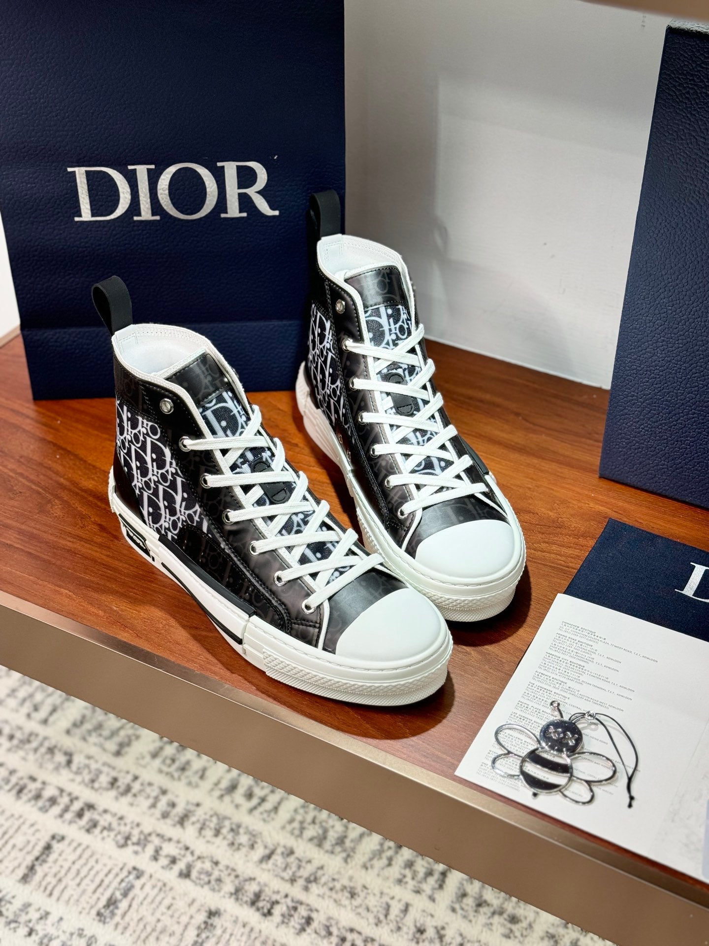 High-top Dior sneakers with black monogram panels, white laces, and ankle heel tab